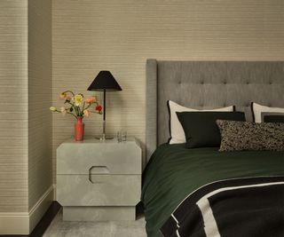 corner of bedroom with neutral textured wallpaper, dark green bedding, gray headboard and nightstand