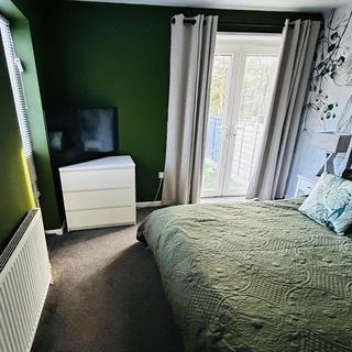 Green bedroom with white chest of drawers