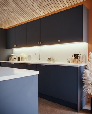 navy blue modern kitchen apartment style with white countertops and under cabinet lighting, wood shiplap style ceiling, brass knobs and handles