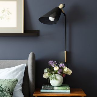 Navy blue bedroom with reading light on wall