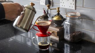 Person pouring water onto V60 coffee filter using gooseneck kettle