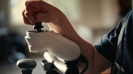 A young boy uses the Xbox Adaptive Joystick, mounted to a tabletop.