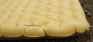 The corner of an inflated yellow Forclaz Inflatable Trekking Mattress MT900.