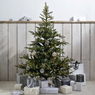 A decorated artificial Christmas tree with wrapped presents piled below