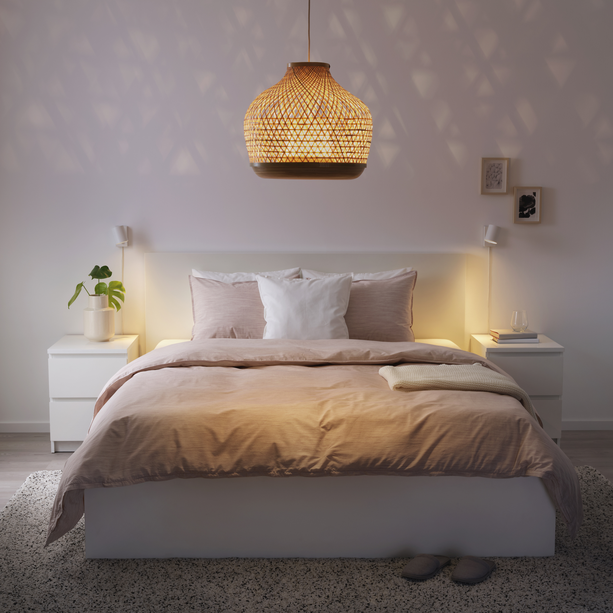 pink and white bedroom with matching side tables, rug, rattan and bamboo ceiling light