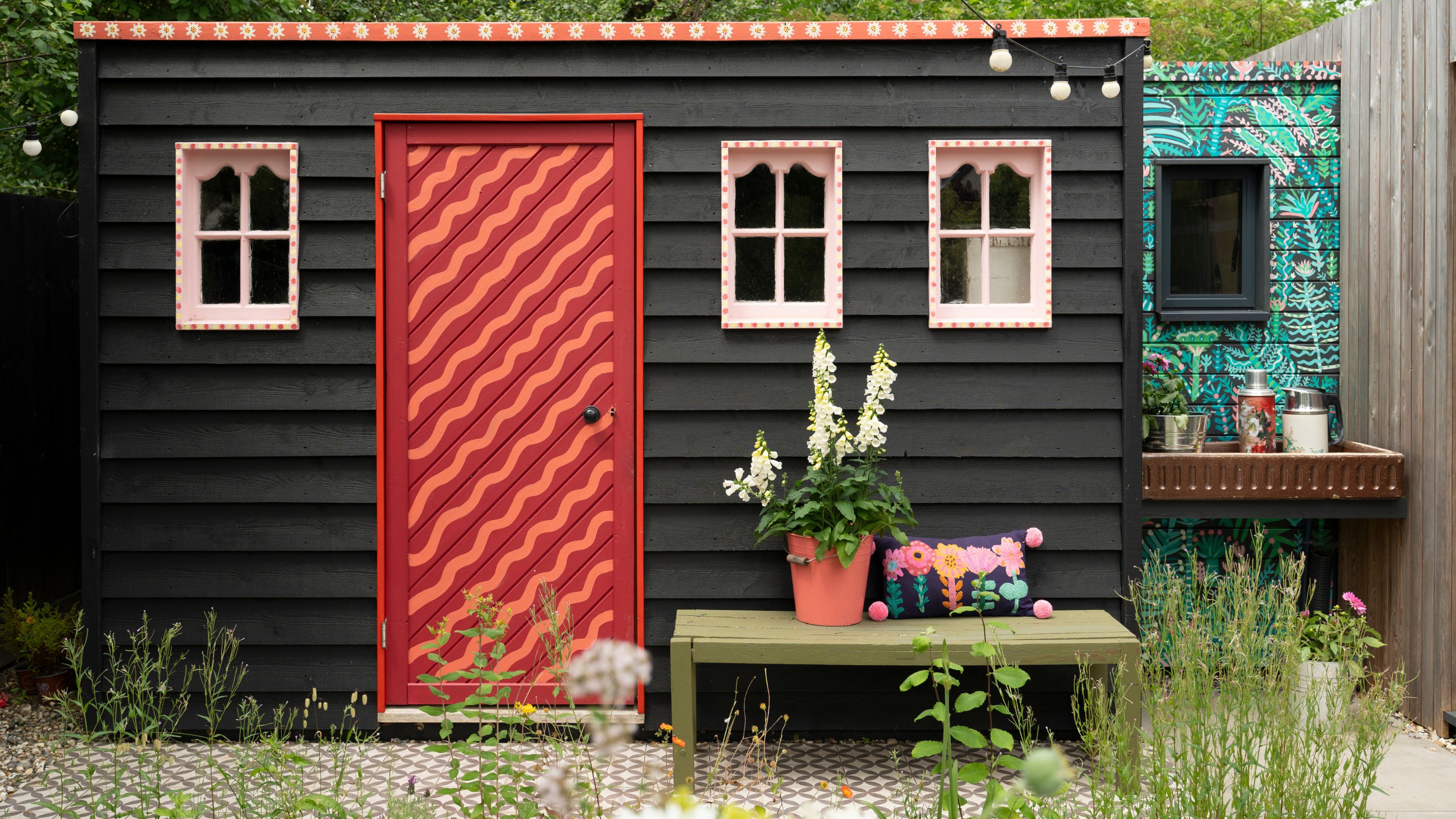 Black cladded shed with brightly painted door and windows