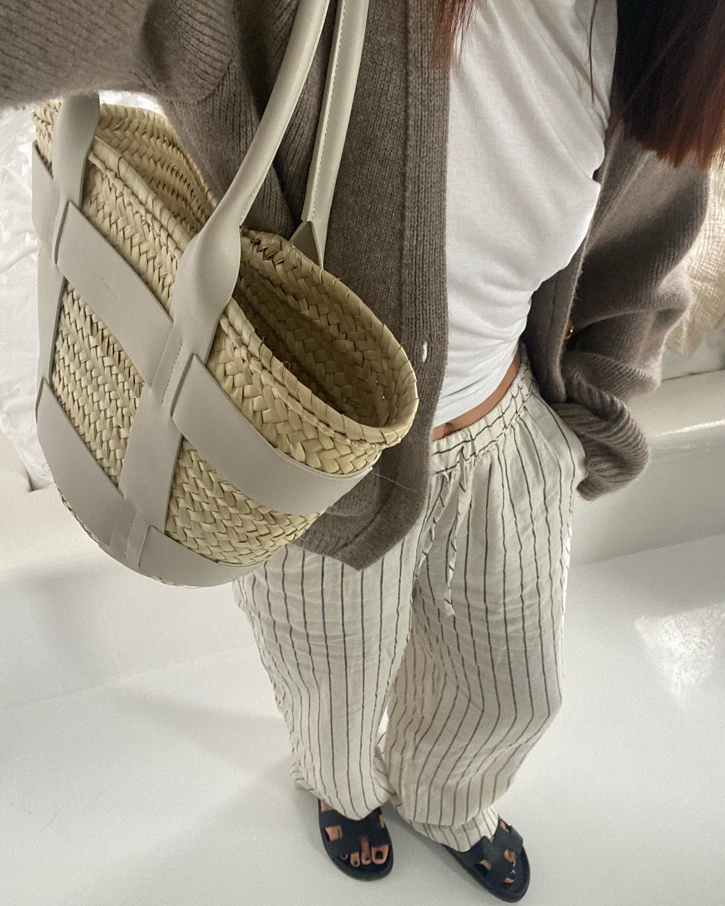Woman wears cardigan, white t-shirt, striped trousers and sandals