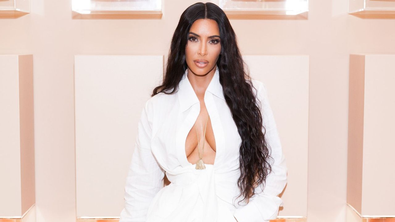 kim kardashian in a white shirt on a pink background