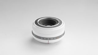 The white TTArtisan 27mm f/2.8 lens on a white background