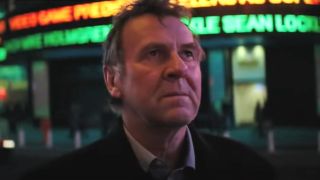 Tom Wilkinson looking up at night in front of a news ticker in Michael Clayton.