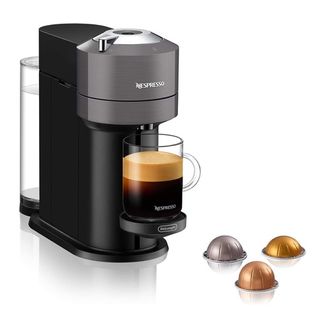 Nespresso Vertuo Next och tre kaffekapslar mot en vit bakgrund.
