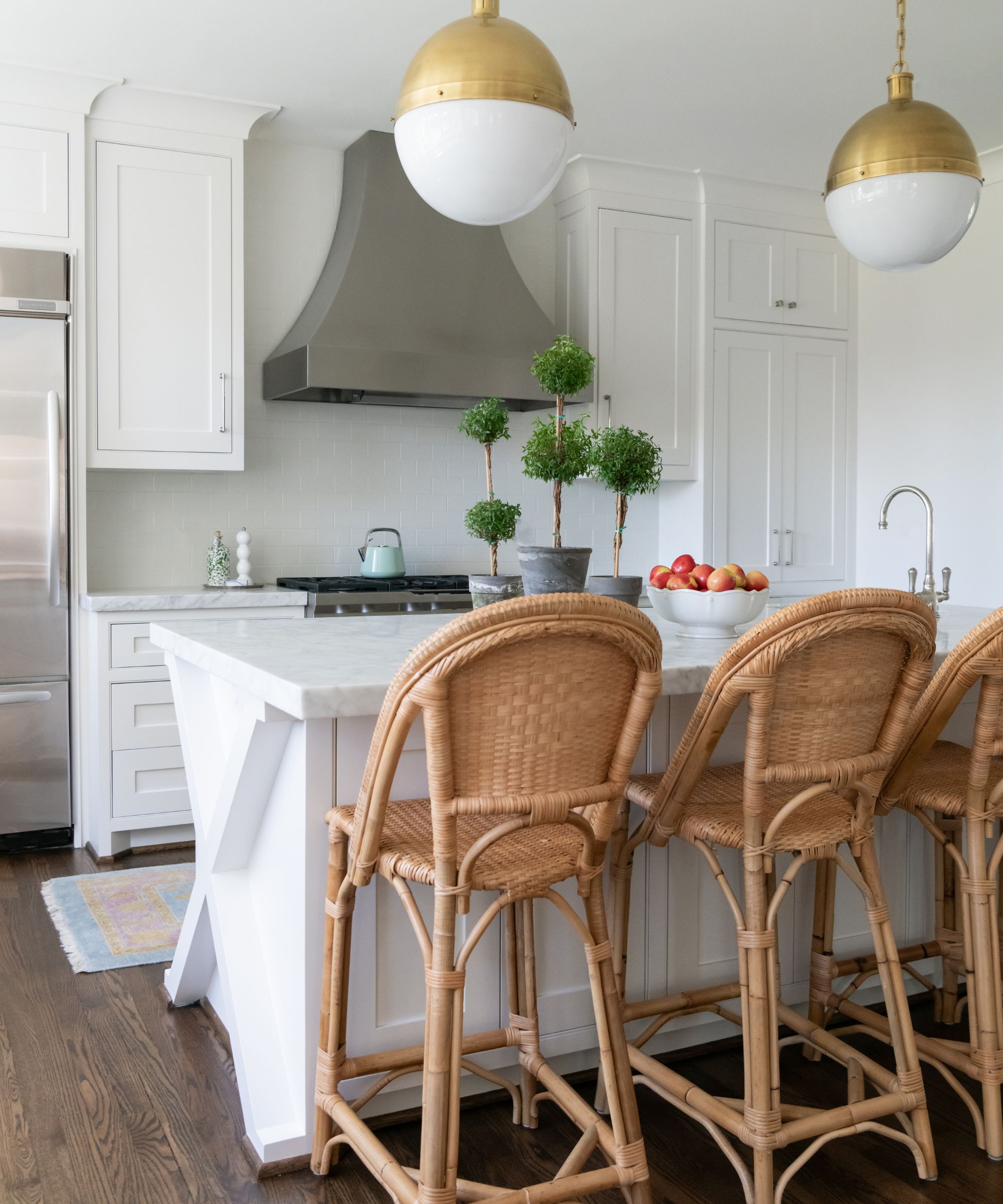 white kitchen cabinets and countertop with rattan bar stools and wooden floor