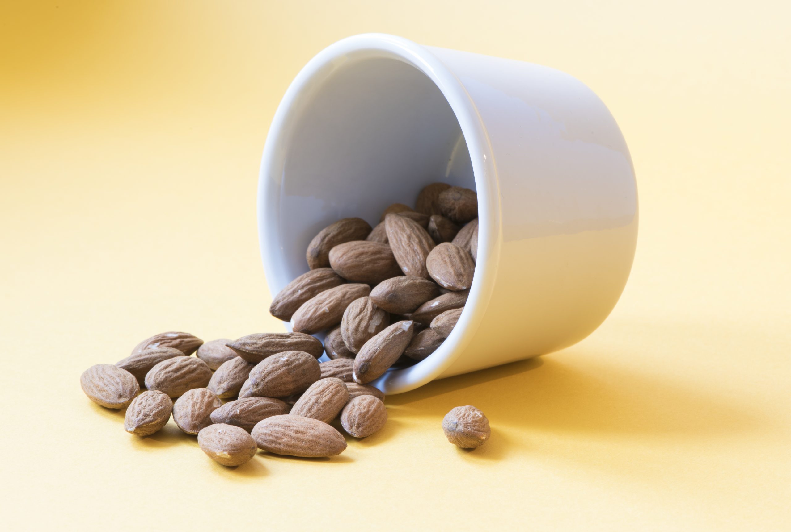 A pot of almonds on a yellow background