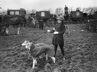 February 1922: At the Waterloo Cup Meeting held at Altcar, near Liverpool, Miss Lucy Brinkley with two greyhounds on the leash and well wrapped up against the cold. (Photo by Topical Press Agency/Getty Images)