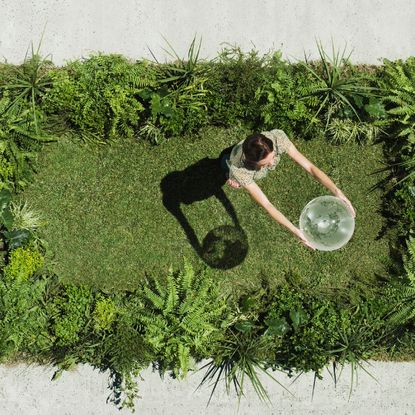 a woman dances on grass holding a glass globe