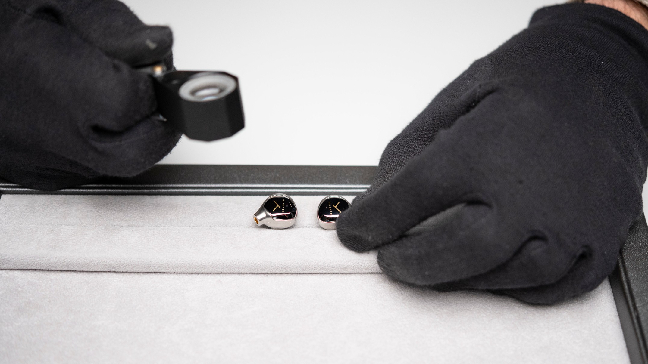 Beyerdynamic Xelento earbuds ona. jewelry tray, with a magnifying glass close by