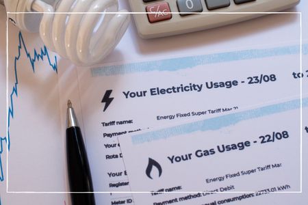 Energy and gas usage documents on a table with a pen, calculator and light bulb