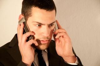 Young man using two mobile phones.