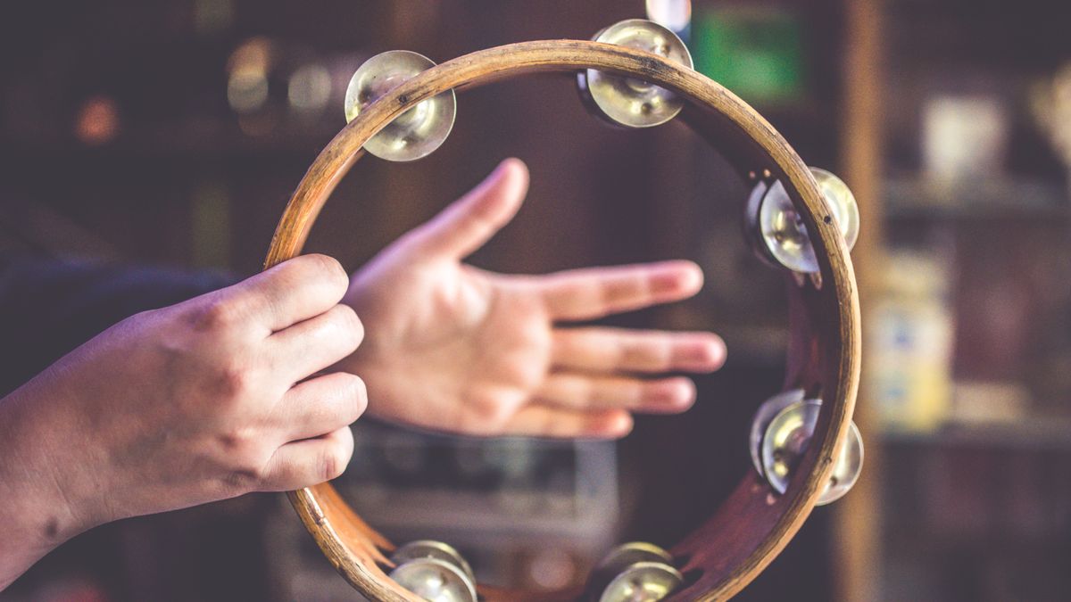 Person holding and playing a wooden headless tambourine