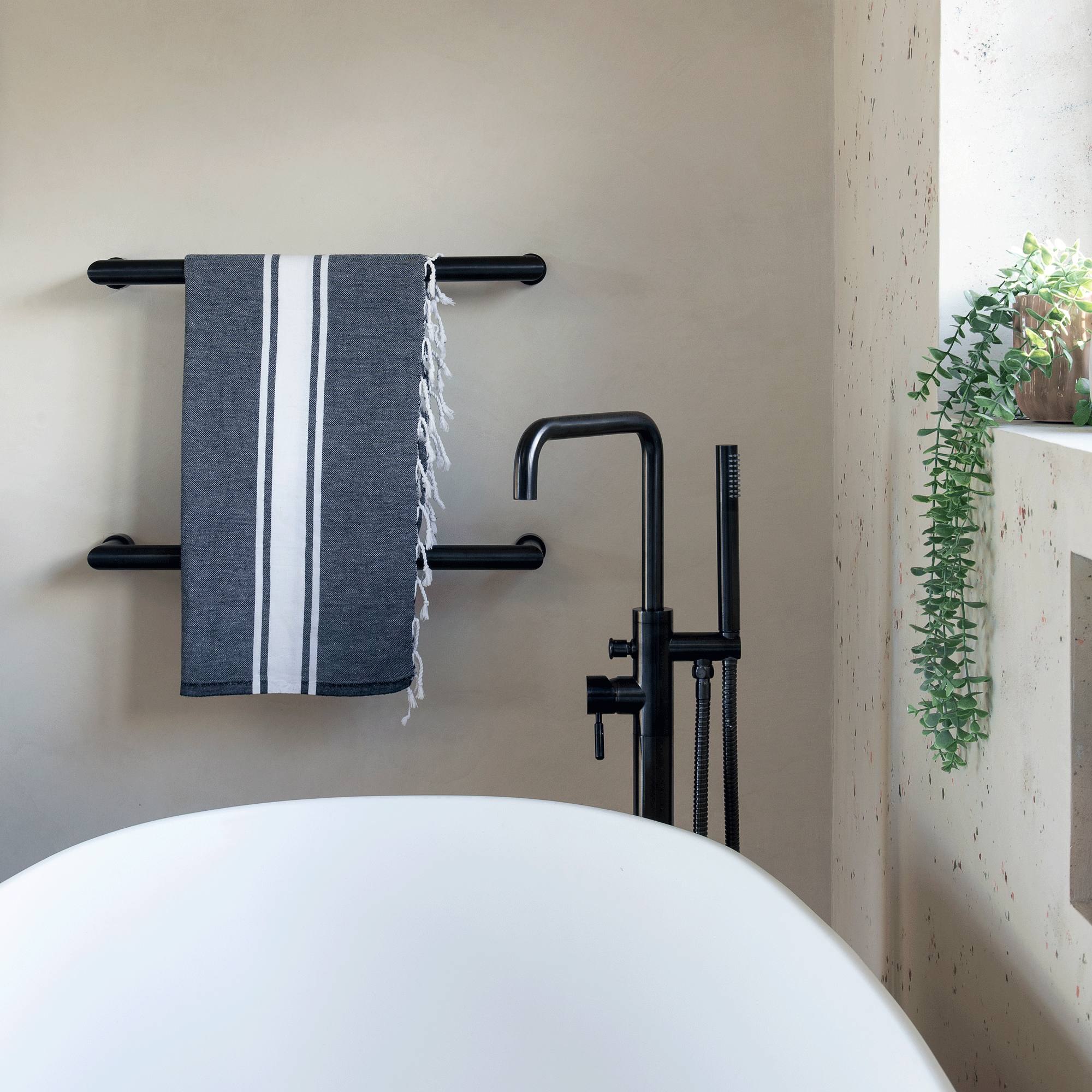 a bathroom with a bath and black fixtures and a blue hammam towel