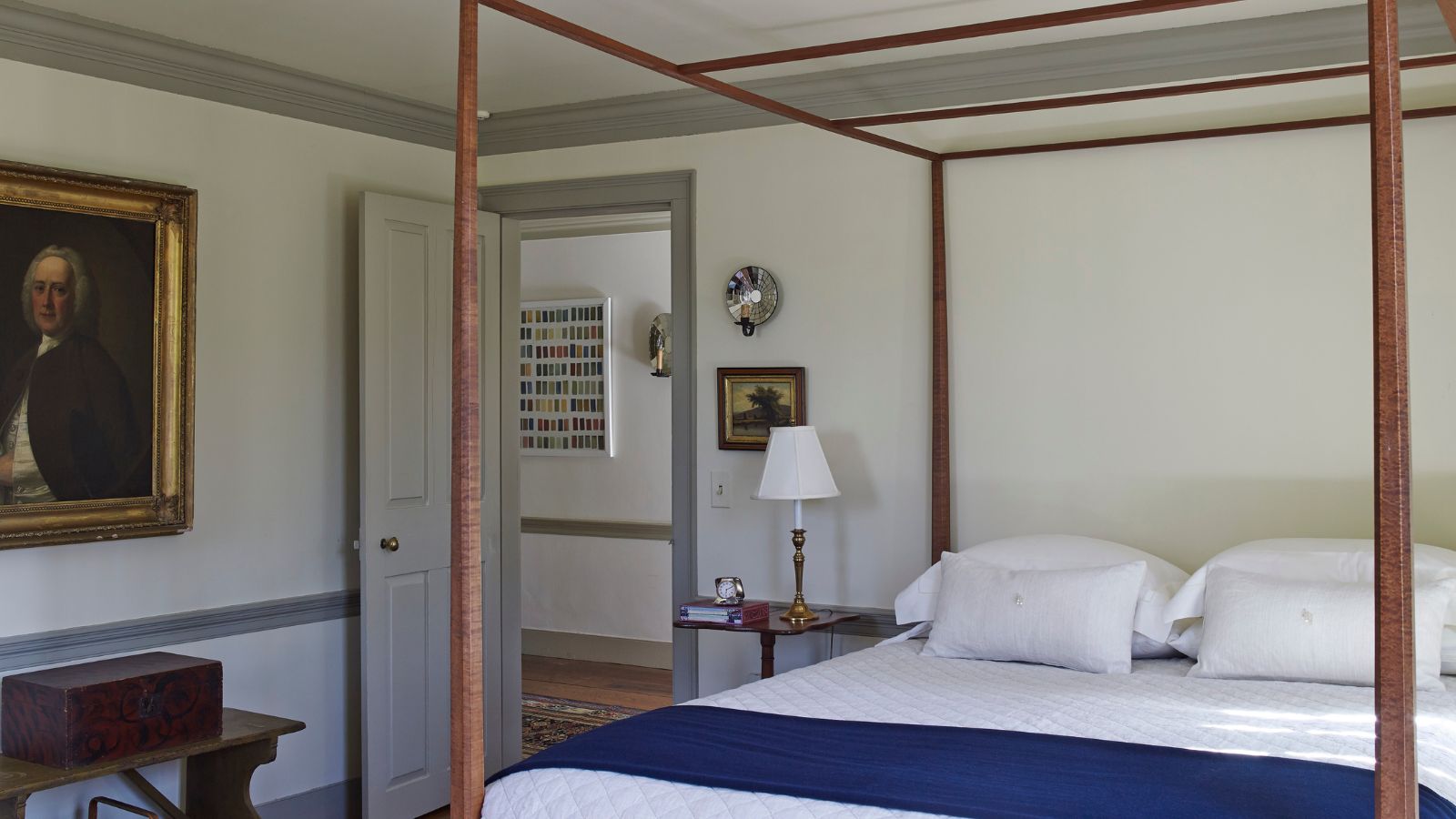 A white bedroom with a wooden four poster bedframe
