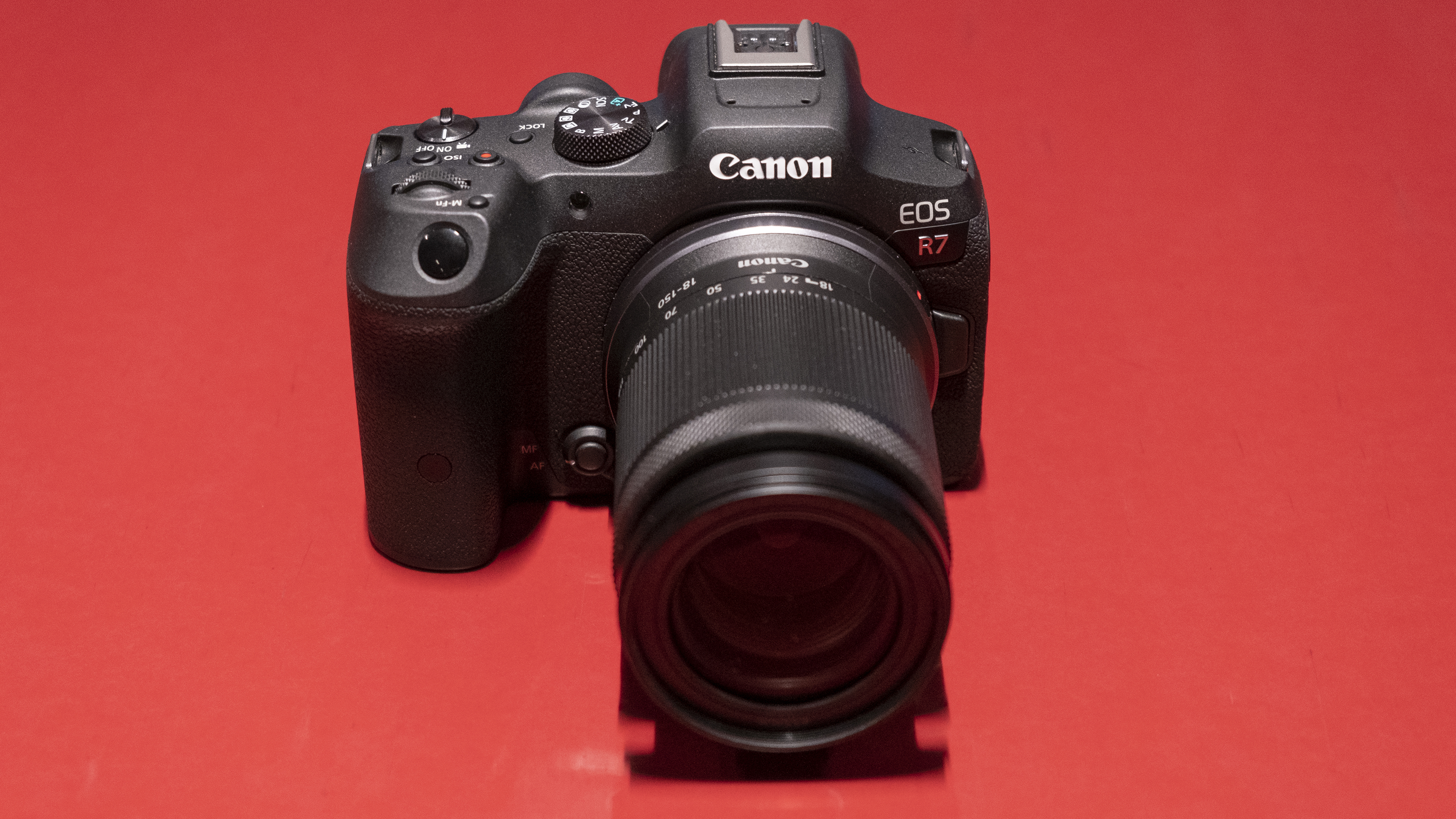 The Canon EOS R7 camera on a red background