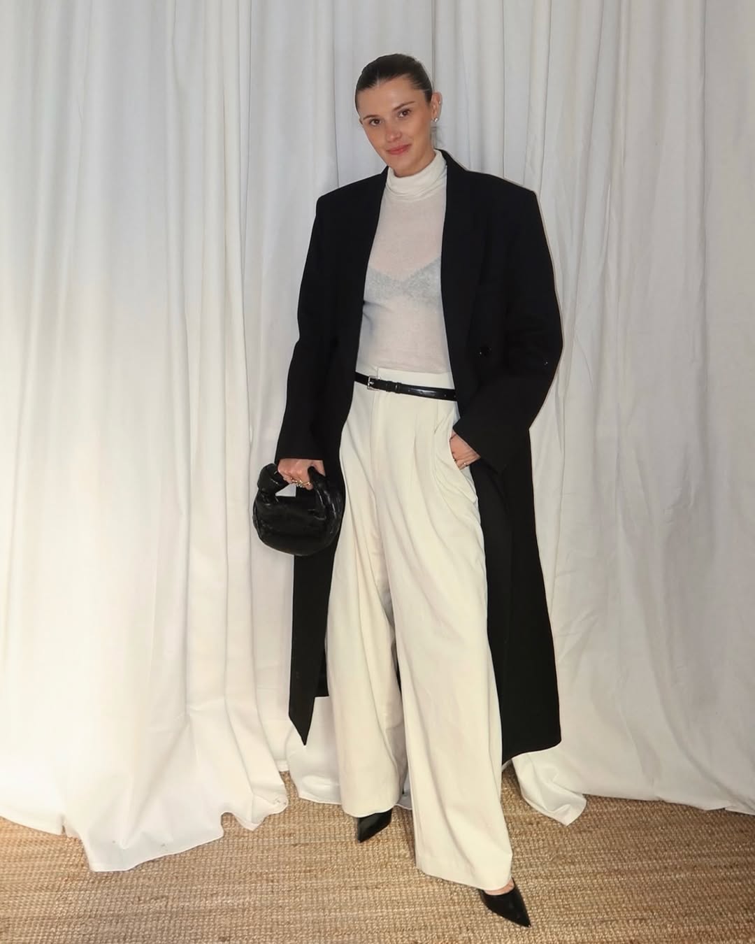 French woman wearing St. Agni white trousers and black long jacket.