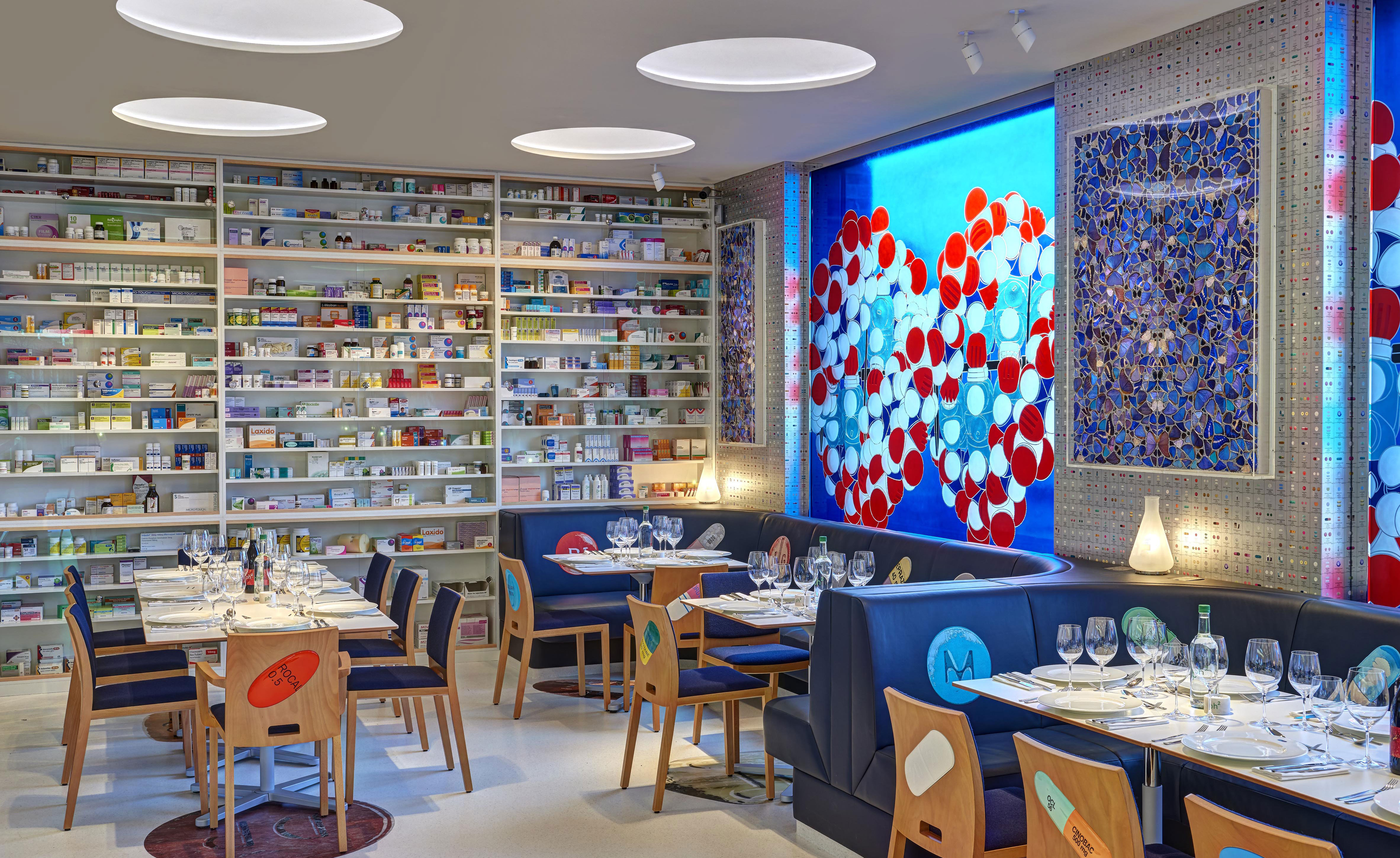 Cabinets stacked full of medicines line the walls, bar stools are topped with giant squishy paracetamol pills and glinting helix strands decorate a bar