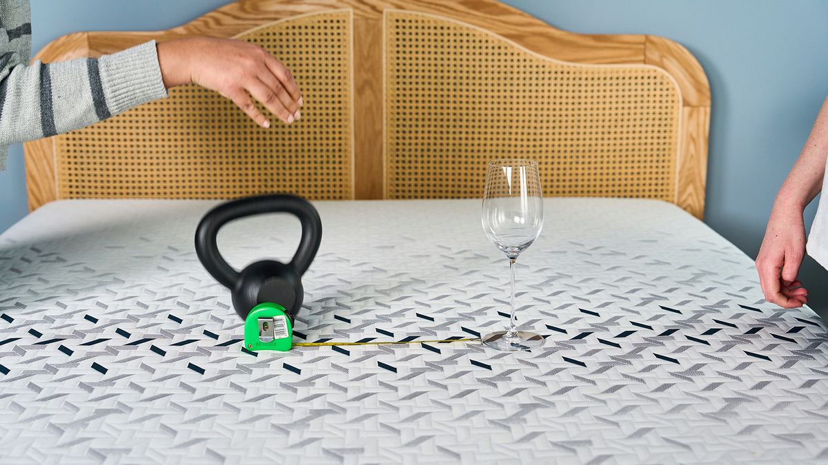 Two Tom's Guide mattress testers dropping a weight next to a wine glass to measure how well the Nectar Ultra Hybrid performs in motion isolation tests