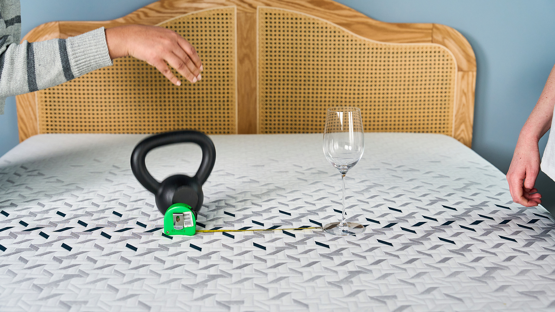 Two Tom's Guide mattress testers dropping a weight next to a wine glass to measure how well the Nectar Ultra Hybrid performs in motion isolation tests