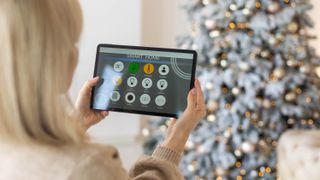Woman holding smart home control looking at a Christmas tree