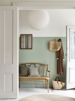 A living room with back wall half painted in a light pastel blue