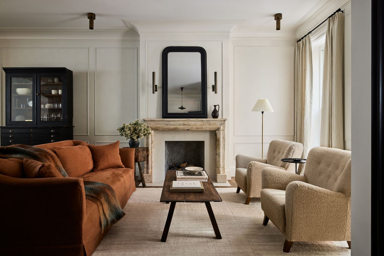 A cream living room with a wooden coffee table, orange accent sofa and neutral palette. 