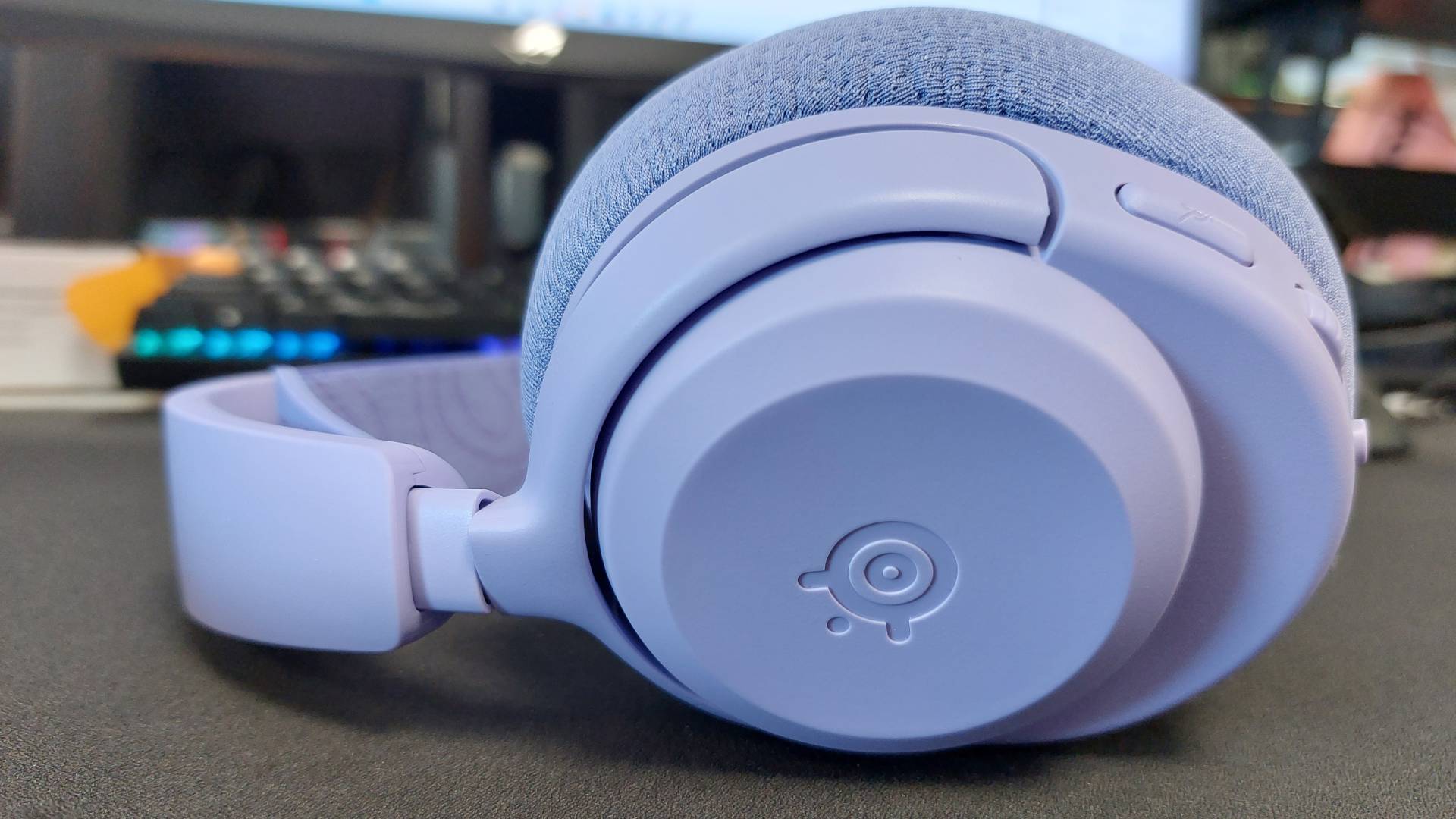 The SteelSeries Arctis Nova 3 X seen on a desk. This is the Lavender colourway.