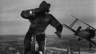 Still from the movie King Kong (1933). This is a black and white image of a giant ape on top of the Empire State Building fighting off a little plane.