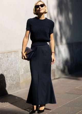 Jenny Walton wears black shiny leather pumps, black sunglasses, a blue short-sleeved sweater, a blue leather bag and a blue long skirt outside Bally show during the Milan Fashion Week Menswear Spring/Summer 2025 on September 21, 2024 in Milan, Italy. (Photo by Valentina Frugiuele/Getty Images)