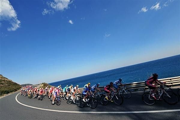 The peloton skirts the coastline.