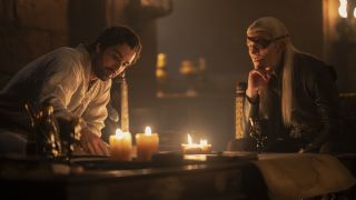Criston and Aemond speak by candlelight as they sit at a table in House of the Dragon season 2