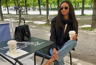 Woman sitting and wearing a black blazer and jeans.