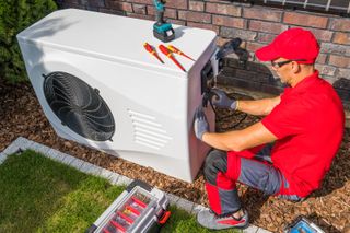 Engineer installing an air source heat pump on the side of a building