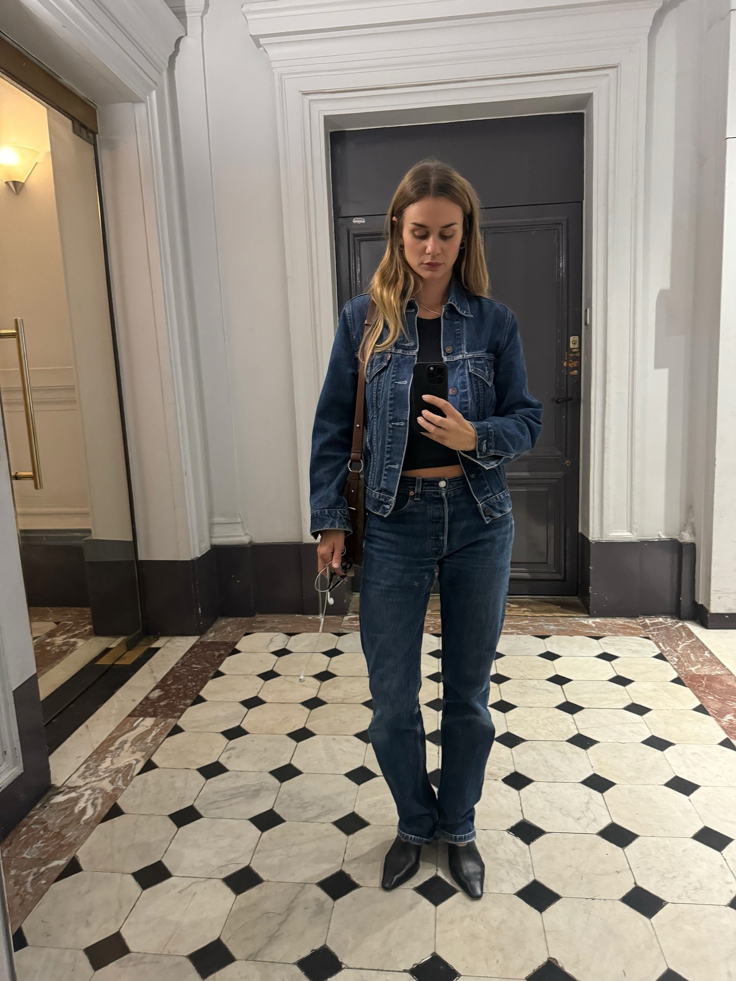 Influencer @annelauremais wears a pair of dark wash jeans with a dark blue denim jacket and black pointed-toe boots.