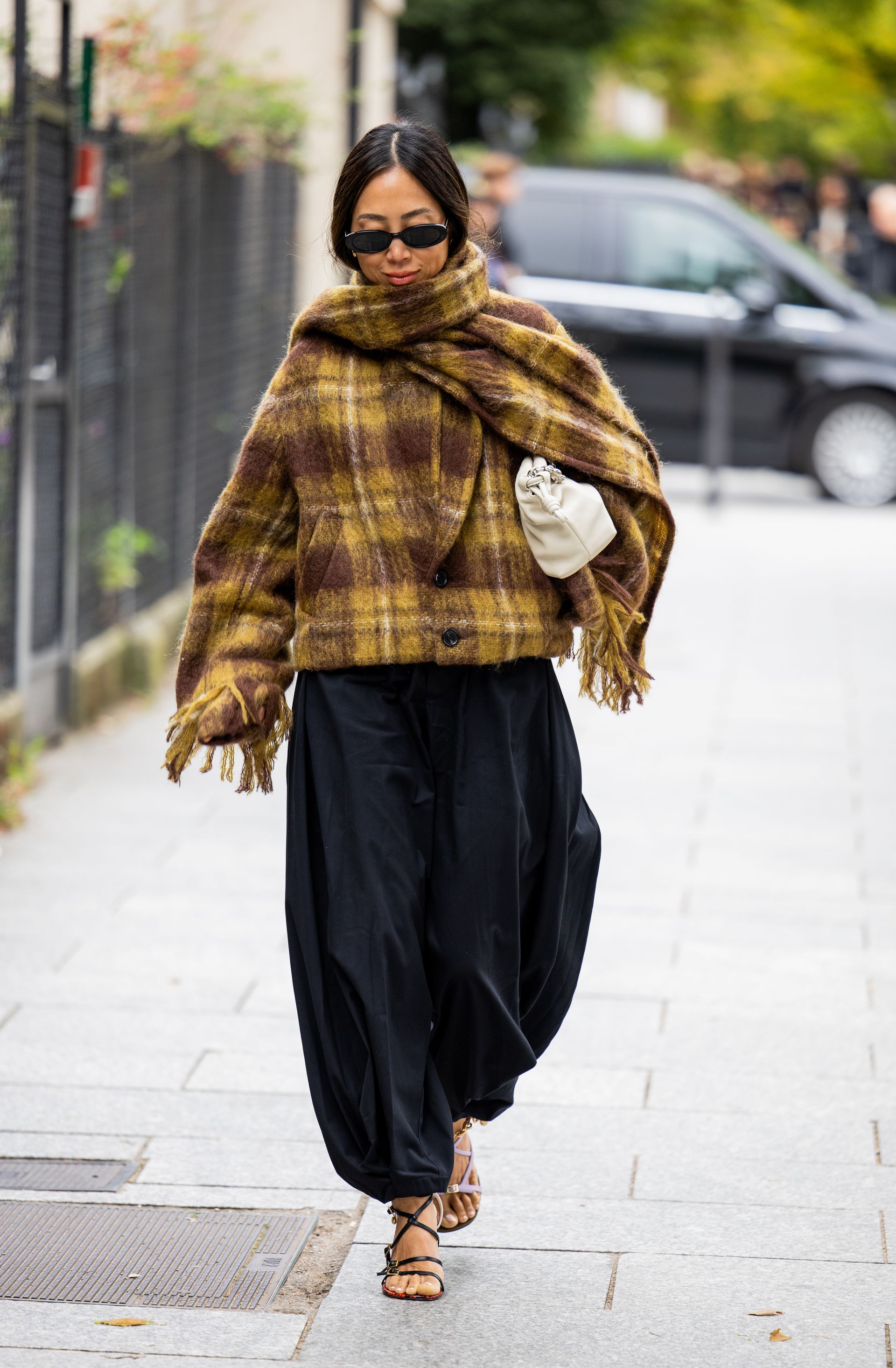 Woman in black balloon pants and brown scarf coat