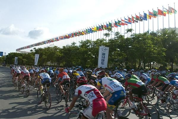 The peloton speed past the flags of countries represented in the Miss World contest.