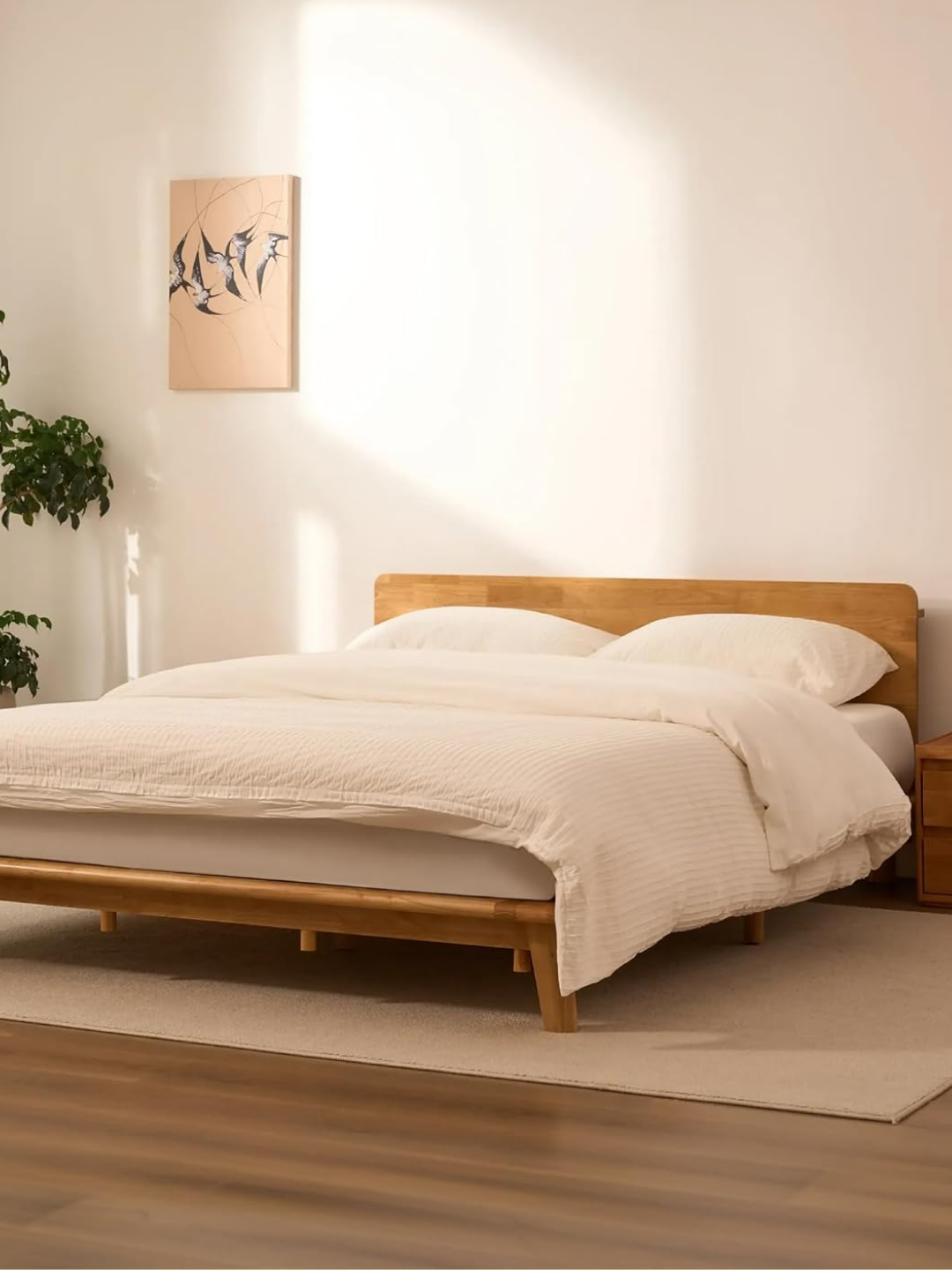 A Japanese joinery bed from FLEXISPOT with white bedding and a potted tree