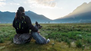 Woman and dog sitting looking at the mountains