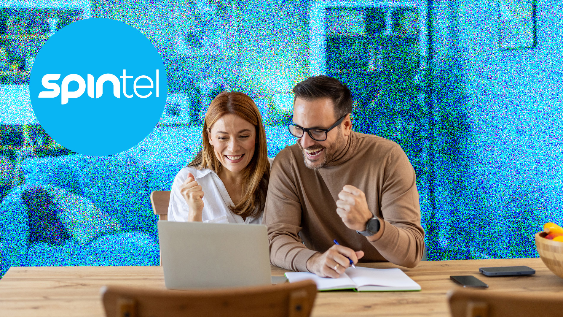 A young couple sitting at a table and cheering while looking at a laptop. The background is blue and the SpinTel logo is in the top left.