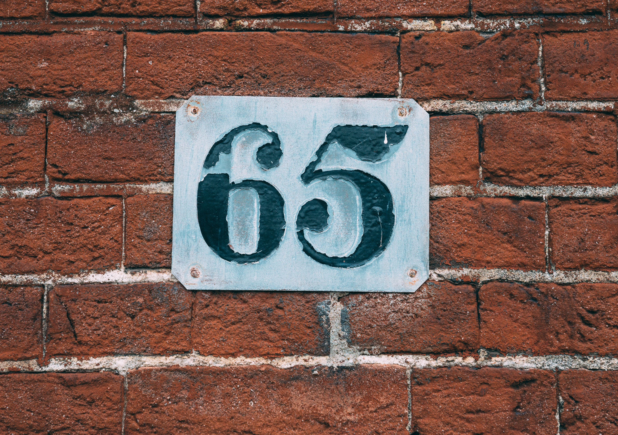 metal number 65 on a brick wall