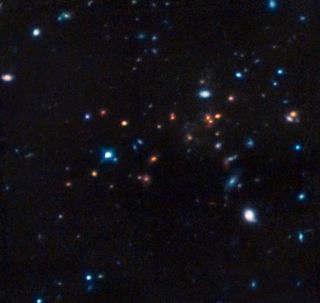 This image from the Hubble Space Telescope shows CL J1449+0856, the most distant mature cluster of galaxies found. The image was taken in infrared light, with color data added from ESO’s Very Large Telescope and the NAOJ’s Subaru Telescope.