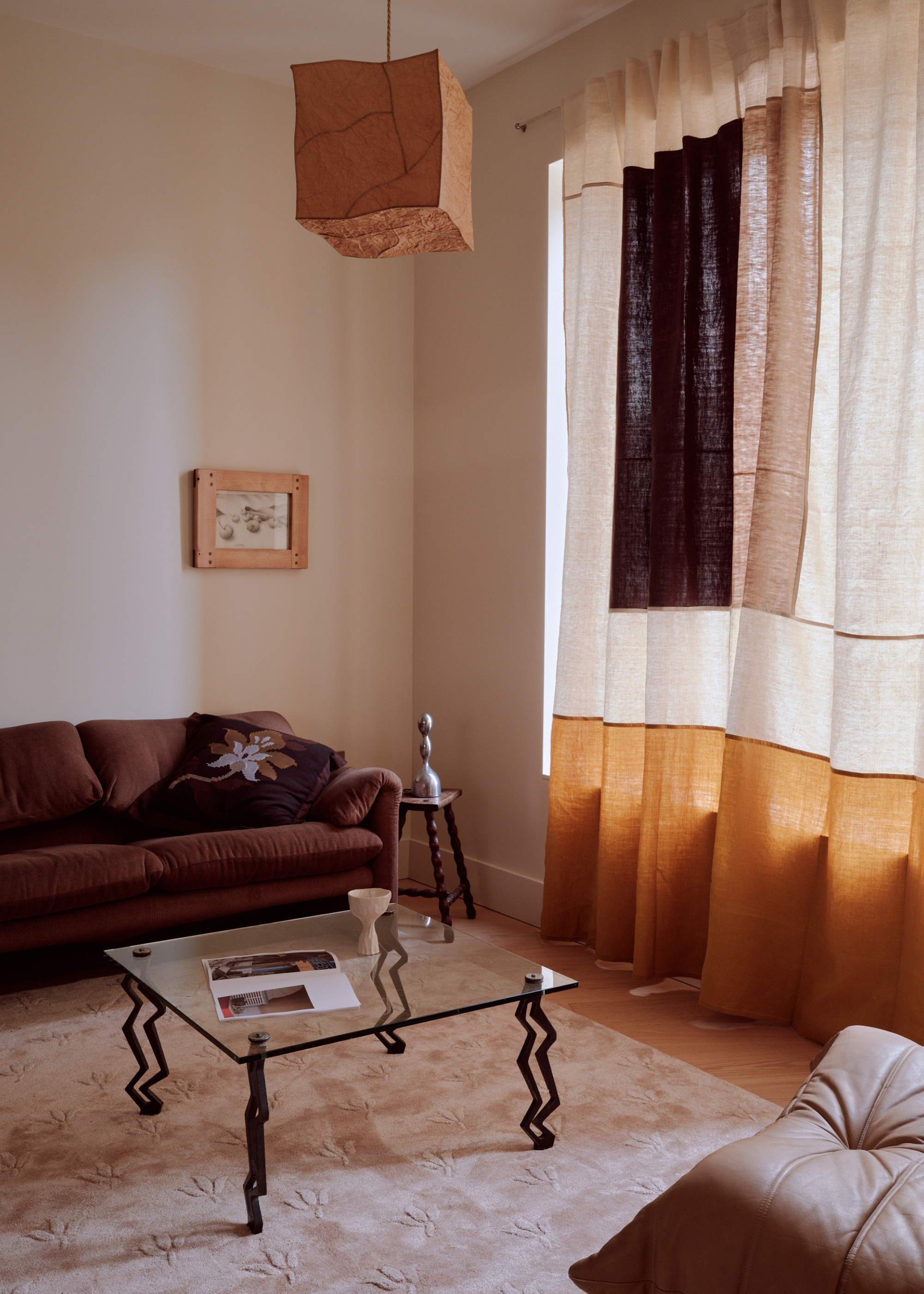 neutral toned living room with linen curtains, a fabric light shade and glass coffee table