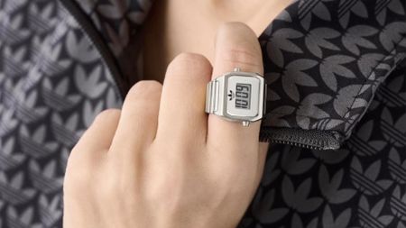 The silver Adidas Digital Watch ring on a person's finger. 